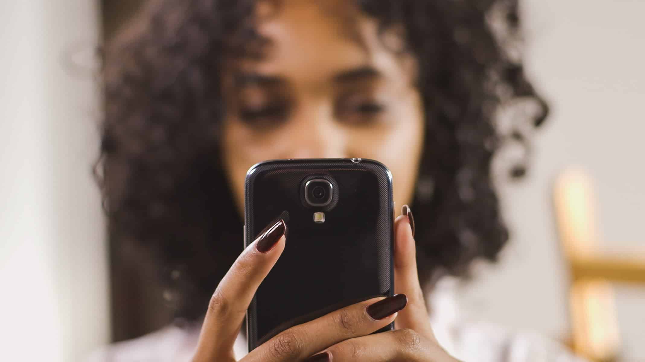 woman holding phone viewing a Mobile-First 'E-Commerce
